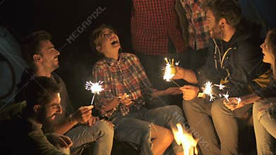 Picnic of young people sitting by the bonfire and and celebrate the New Year