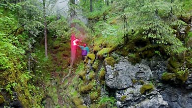 Man with signal fire in nature. Stock footage. Top view of lost traveler in forest and in despair he lit red smoke bomb