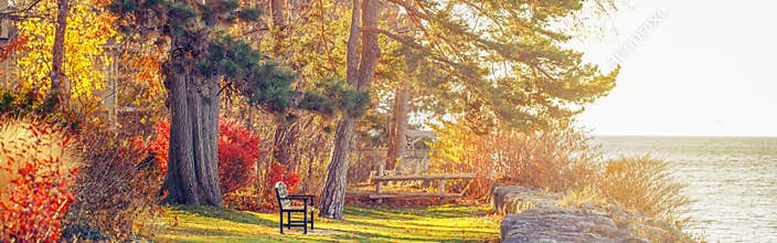 Park with one lonely old bench on bank shore near water lake. Web header banner for website