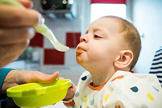 Festive meal. Mother feeding baby solid food for the first time