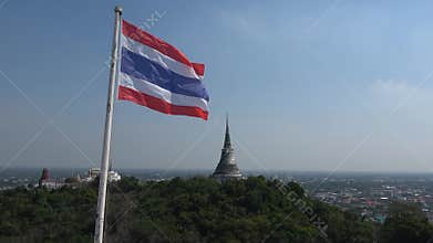 Thai flag flies against the background of a Buddhist temple. Phetchaburi