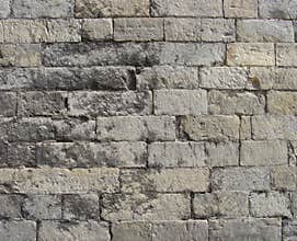 Worn very old large stone wall in gray and beige