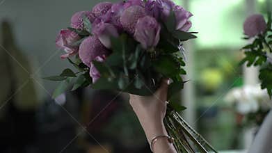 Back view of cute young woman florist wearing apron compose new bouquet.