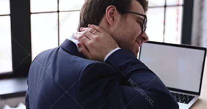 Tired businessman rubbing stiff sore neck tensed muscles in office