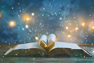Old opened book, heart shaped paper sheets, dark background with stars toned vintage selective focus