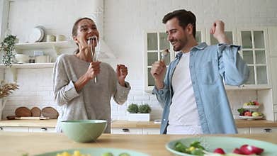 Overjoyed young married couple singing in different utensils.