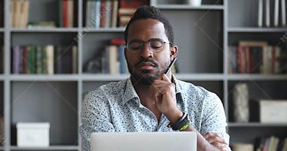 Pensive young biracial man looking at laptop screen.