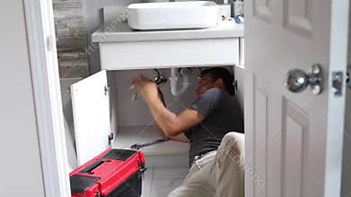 Plumber Working on Sink in Bathroom