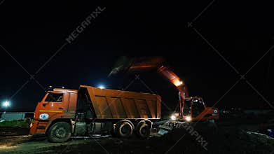Excavator loads truck workbody with ground at construction