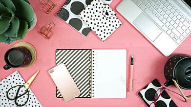 Desktop workspace with laptop and modern pink, black and white accessories.