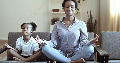 Ethnicity family mindful african mom teaching cute black kid daughter doing yoga exercise at home, calm healthy mixed