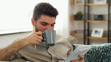 Man writing to notebook and drinking coffee at home