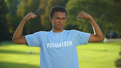Joyful young activist showing power gesture, volunteers cooperation, support