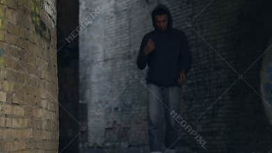 Afro-american male teen in hoodie feeling lonely walking abandoned city building