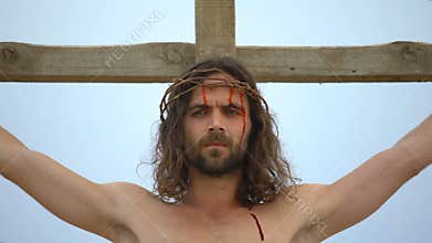 Jesus nailed to cross looking to sky, blood drops flowing down face, crucifixion