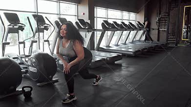 Charming plus size sportswoman stretching at the gym