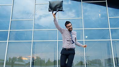 Cheerful young man having fun outdoors dancing enjoying business victory at work