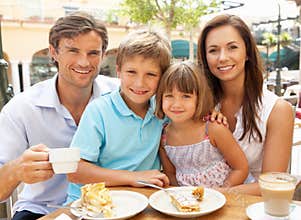 Young Family Enjoying Cup Of Coffee And Cake