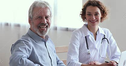 Smiling senior male patient visiting female doctor looking at camera