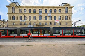 A tram and a cyclist pass the Academy of Arts, Architecture and Design Building in Prague
