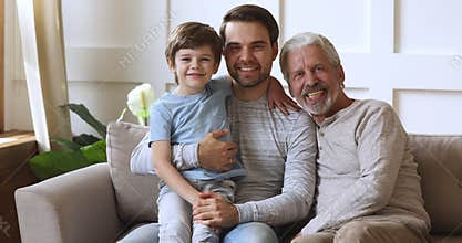 Smiling excited three male generations family resting on couch.