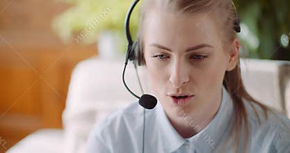 Sales representative in headset speaking to client and making video conference call on laptop.