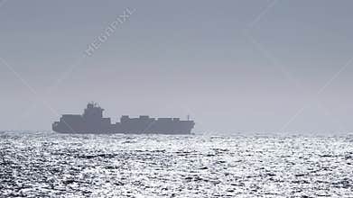Cargo shipping boat sailing and delivering containers all around the world. Transportation across the ocean. Silhouette