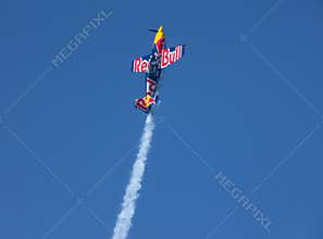 A Red Bull stunt plane trailing smoke during an aerobatic display.