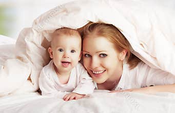 Happy family. Mother and baby playing under blanket