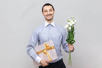 Smiling happy man with present box and bouquet of flowers, congratulate her girlfriend with birthday
