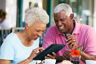 Senior Couple Using Tablet At Outdoor Cafe