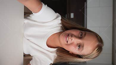 Vertical POV cute cheerful little child girl with holding phone looking at camera, greeting and talking to friends or
