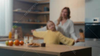 Blurred defocused view family mom and little daughter enjoy funny dance in kitchen together. Mother woman babysitter