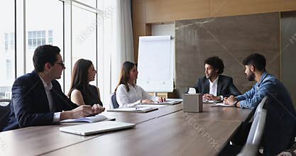 Five multinational teammates lead conversation during morning briefing