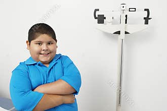 Boy Standing By Weighing Scale In Clinic