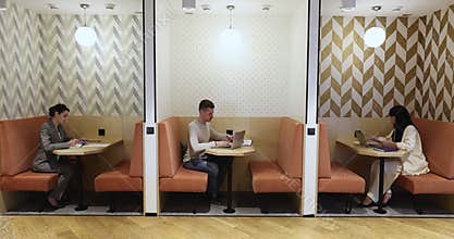 Employees working in separate booths in freelance cafe