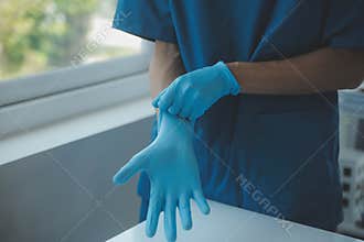 Doctor or nurse putting on blue nitrile surgical gloves, professional medical safety and hygiene for surgery and medical exam on