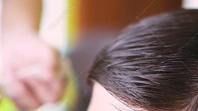 hairstylist using golden scissors and a comb to create bangs for a young man