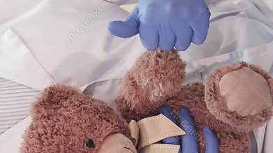 Caring doctor holds a teddy bear and gives a thumbs-up
