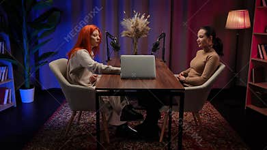 Two Influencers of women being interviewed in a loft-style podcast studio