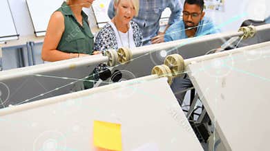 Design team examining pulley model in design studio, displaying digital node network overlay