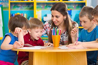 Cute children drawing with teacher at preschool class