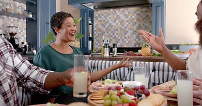 Group of friends enjoying meal together, laughing and sharing drinks at home