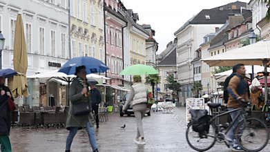 people walking on a rainy day with cafes and colorful buildings in the background