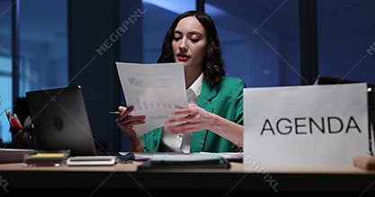 Businesswoman works with documents at desk with Agenda sign