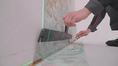 Trimming excess paper. Trimming wallpaper in the corners of a room after wallpapering.