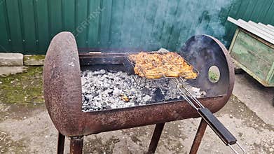 Marinated Chicken Pieces Grilling on Rusty Metal Barrel Barbecue in Backyard