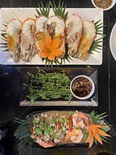 Grilled prawn platter with herb garnish and dipping sauce in dark restaurant setting