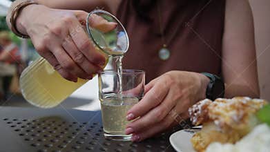 Girl Pouring Fresh Lemonade Into A Glass At An Outdoor Cafe