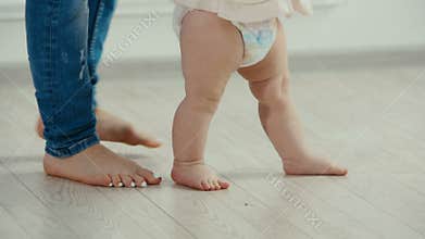 Legs of mother and baby. The baby`s first steps
